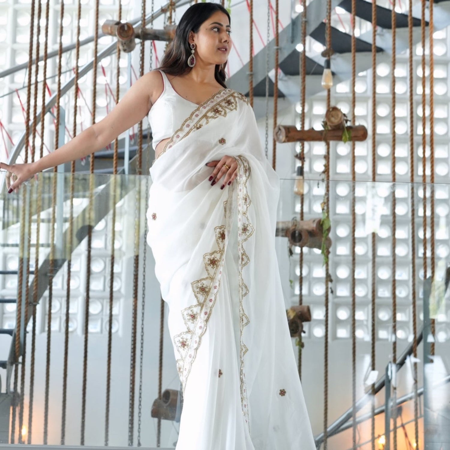 Woman wearing a white organza saree with gold gota patti and sequin border, styled with a matching blouse, perfect for wedding or festive occasions.